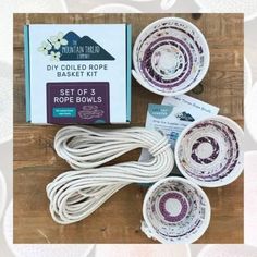 four bowls with white and purple designs sitting on top of a wooden table next to a box