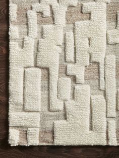 a white rug on top of a wooden floor next to a brown and white wall