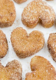 some sugared donuts are arranged in the shape of a heart on a white surface