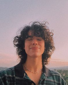 a woman with curly hair standing in front of the camera