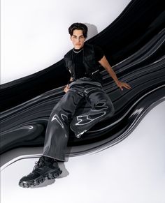 a young man sitting on top of a black and white wave design floor mat with his legs spread out