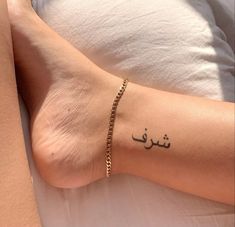 a woman's foot with arabic writing on it and a gold chain around her ankles