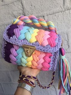 a person holding up a multicolored purse