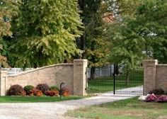 a gated driveway with flowers and trees in the background