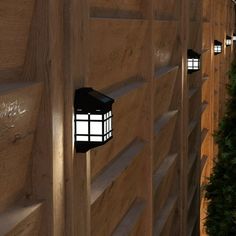 three lights are attached to the side of a wooden wall with plants growing on it