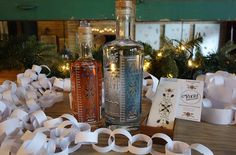 two bottles of alcohol sitting on top of a table next to white ribbons and greeting cards