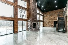 an empty room with large windows and a stone fire place in the center, surrounded by wood paneling