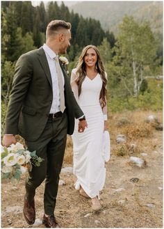 a bride and groom walking in the mountains holding hands with each other while they hold hands