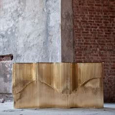 a gold bench sitting in front of a brick wall