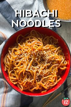 a red bowl filled with noodles next to a pot of soup and two spoons