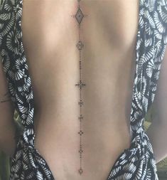 the back of a woman's neck with a cross tattoo on it