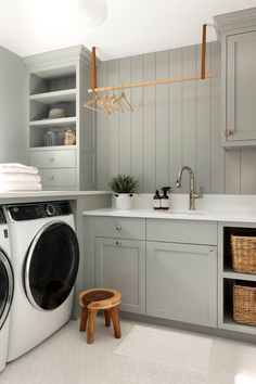 a washer and dryer in a small room with gray cupboards, white counter tops and drawers