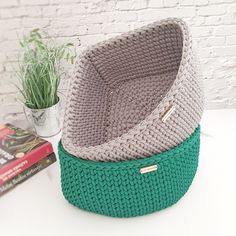 two knitted baskets sitting on top of a table next to a potted plant