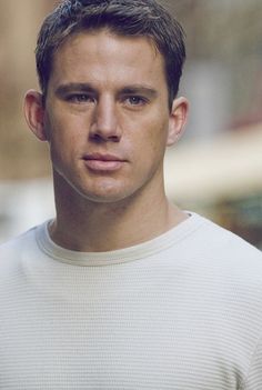 a man in a white sweater looking at the camera