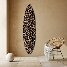 a leopard print surfboard hanging on the wall next to a chair