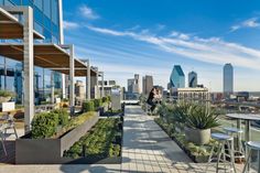 people are sitting at tables on the roof of a high rise building with cityscape in the background