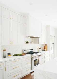 a kitchen with white cabinets and marble counter tops