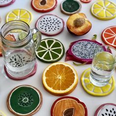 several slices of fruit are arranged on a table with water and glassware next to them