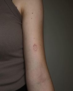 a woman's arm with a small heart tattoo on the left side of her arm