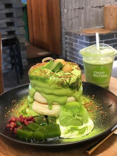 there is a cake with green icing on the plate next to a cup of juice