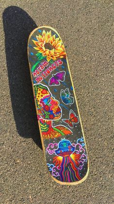 a skateboard is laying on the ground with designs painted on it's side