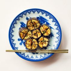 a blue and white plate topped with food next to chopsticks