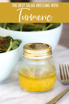 the best salad dressing with tumerice in a glass jar next to a bowl of greens