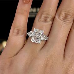 a woman's hand with a diamond ring on top of her finger and an engagement band