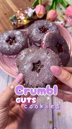 a person is holding up some cookies on a pink plate