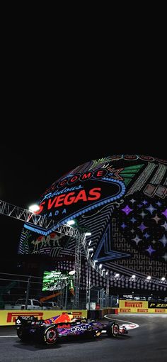 the las vegas sign lit up at night with cars driving around it in front of it