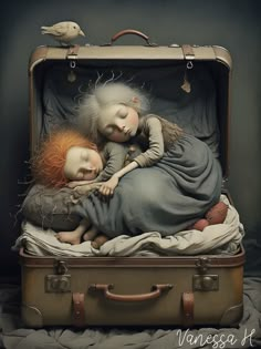 two dolls are sleeping in an old suitcase