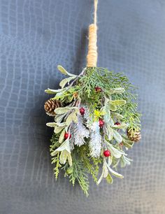 a christmas wreath hanging on a wall with pine cones and evergreens attached to it