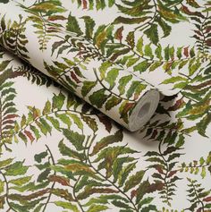 a roll of wrapping paper sitting on top of a leafy wallpaper covered in green and red leaves