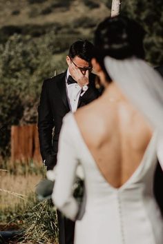 a man in a tuxedo standing next to a woman wearing a wedding dress