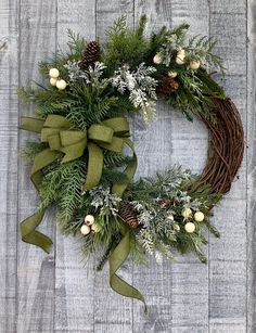 a christmas wreath with pine cones and greenery on a wooden background, ready to be hung