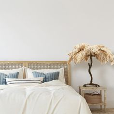 a bed with white sheets, pillows and a palm tree on the headboard next to it