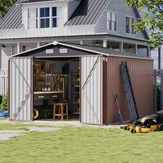 a large metal shed sitting on top of a lush green field next to a house