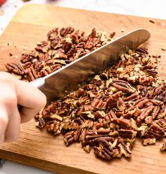 someone is cutting up some pecans on a wooden board