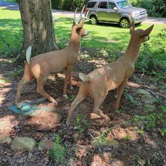 two statues of deer standing next to a tree