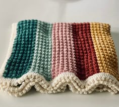 a multicolored crocheted dishcloth on a white surface