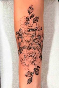 a woman's arm with flowers and an owl tattoo on the left side of her arm