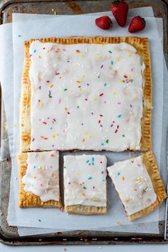 some food is laying out on a baking sheet with icing and sprinkles