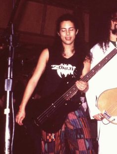 two people standing next to each other holding guitars