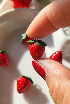 a person's finger with some tiny strawberries on it