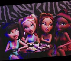 three barbie dolls sitting at a table eating cake