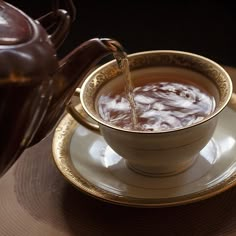 a teapot pouring water into a cup on a saucer