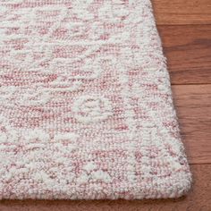 a red and white rug is laying on the floor next to a brown wooden floor