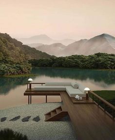 an outdoor lounge area overlooking a lake with mountains in the background