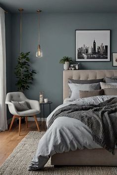 a bedroom with blue walls and grey bedding, white curtains, gray chair, and rug