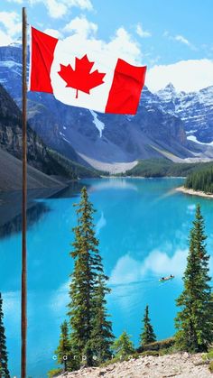 a canadian flag flying over a lake with mountains in the background